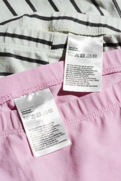 Photo of Clothing labels with instructions on garments, top view