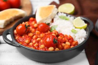 Delicious chickpea curry with rice on white wooden table, closeup