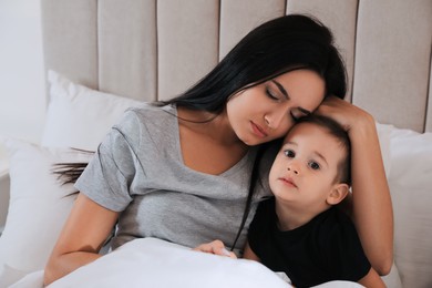Depressed single mother with child in bed at home