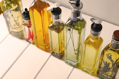 Bottles of different cooking oils on white wooden table, closeup