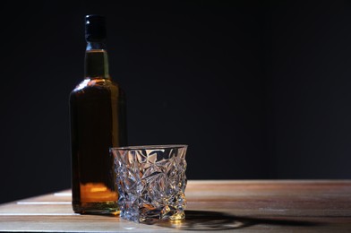 Whiskey on wooden table against dark background, space for text. Alcohol addiction