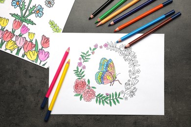 Coloring pages with children drawings and set of pencils on grey table, flat lay