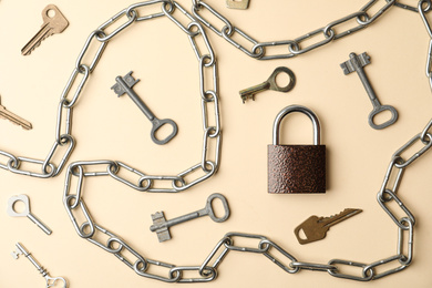 Steel padlock, keys and chain on beige background, flat lay. Safety concept