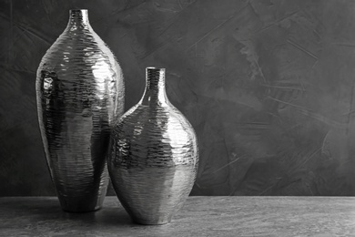 Stylish silver ceramic vases on grey table, space for text