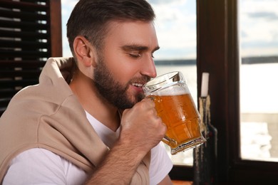 Young man drinking tasty beer in pub
