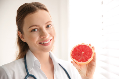 Nutritionist with grapefruit near window in office