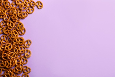 Delicious pretzel crackers on violet background, flat lay. Space for text