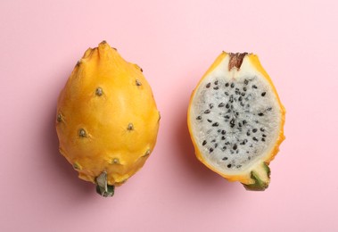Photo of Delicious cut and whole dragon fruits (pitahaya) on pink background, flat lay