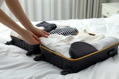 Woman packing suitcase for trip in bedroom, closeup