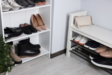 Photo of Shelving unit and shoe storage bench near white wall in hallway. Interior design