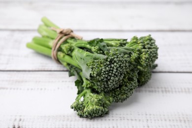 Photo of Fresh raw broccolini on white wooden table, closeup. Healthy food