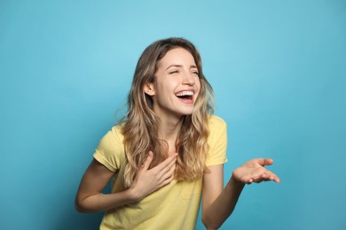Cheerful young woman laughing on light blue background