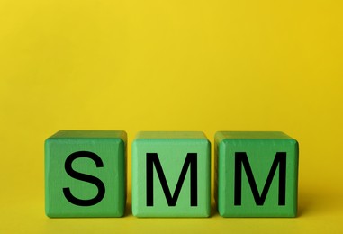 Green cubes with abbreviation SMM (Social media marketing) on yellow background