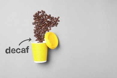 Word Decaf and arrow pointing at takeaway paper cup with coffee beans on light grey background, flat lay. Space for text