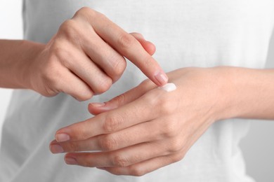 Photo of Woman applying cream onto hand, closeup view