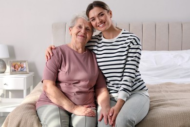 Young caregiver and senior woman in bedroom. Home care service