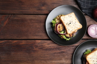 Delicious eggplant sandwiches on wooden table, flat lay. Space for text