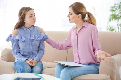 Female psychologist working with teenager girl in office