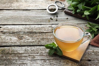 Photo of Cup of hot aromatic mint tea on wooden table. Space for text