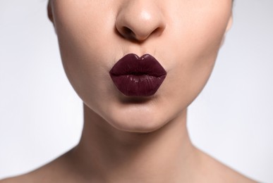 Young woman with beautiful lips makeup on light background, closeup