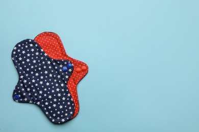 Reusable cloth menstrual pads on light blue background, flat lay. Space for text