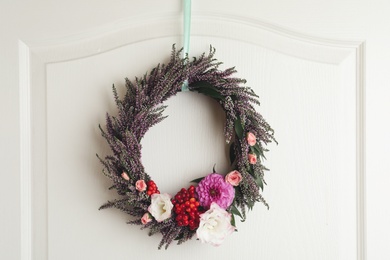 Beautiful autumnal wreath with heather flowers hanging on white wooden door. Space for text