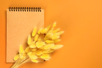 Notepad with decorative plants on colorful background, top view. Space for text