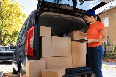 Courier counting packages near delivery truck outdoors