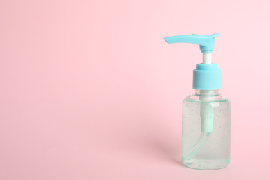 Photo of Dispenser bottle with antiseptic gel on pink background. Space for text