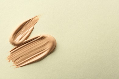 Sample of liquid skin foundation on beige background, top view. Space for text