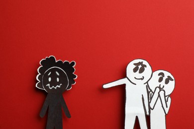 White paper figures mocking at black one on red background, flat lay. Racism concept