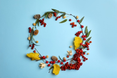 Dried flowers, leaves and berries arranged in shape of wreath on light blue background, flat lay with space for text. Autumnal aesthetic