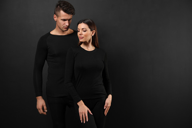 Couple wearing thermal underwear on black background. Space for text
