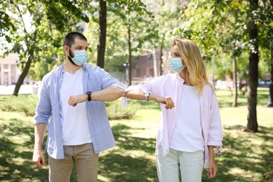 Man and woman bumping elbows to say hello outdoors. Keeping social distance during coronavirus pandemic