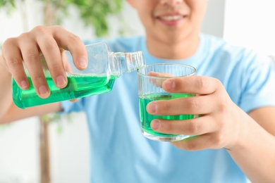 Man pouring mouthwash from bottle into glass, closeup. Teeth care