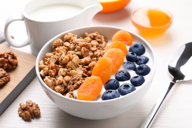 Delicious granola with fruits on white wooden table, closeup