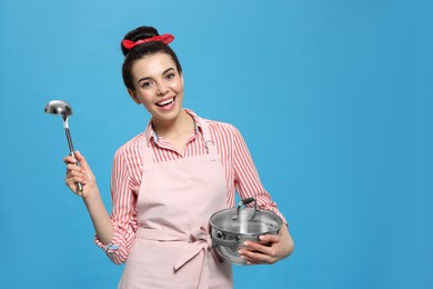 Housewife with pan and ladle on light blue background