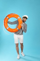 Photo of Sailor with ring buoy on light blue background