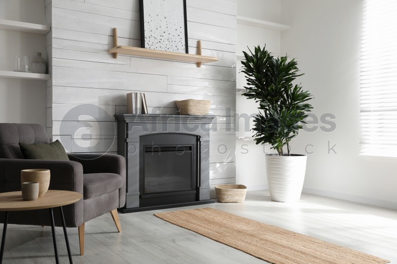 Photo of Cozy living room interior with comfortable armchair and modern electric fireplace