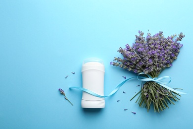 Female deodorant and lavender flowers on light blue background, flat lay