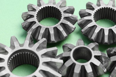 Photo of Different stainless steel gears on light green background, closeup