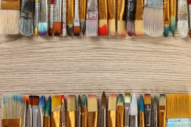Set of different paintbrushes on wooden table, flat lay. Space for text