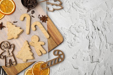 Christmas treat. Flat lay composition with cookie cutters and baked biscuits on white textured table, space for text