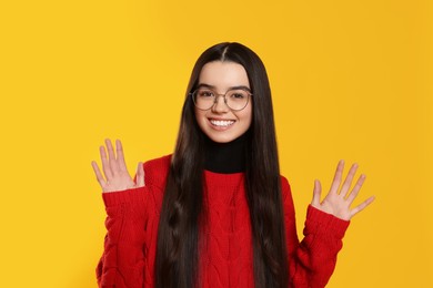 Photo of Portrait of happy teenage girl wearing glasses on yellow background