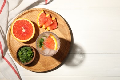 Delicious refreshing drink with sicilian orange and mint near fresh ingredients on white wooden table, flat lay. Space for text
