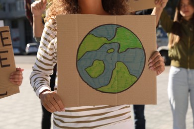Photo of African American woman with poster protesting against climate change outdoors, closeup