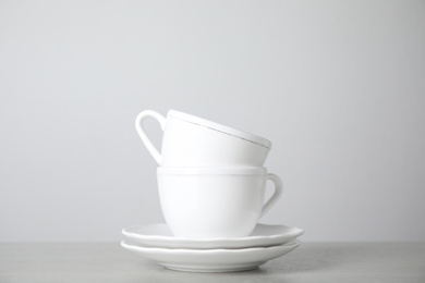 Ceramic saucers and cups on table against white background