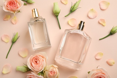 Flat lay composition with different perfume bottles and fresh flowers on beige background