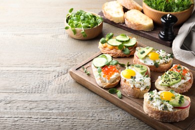 Different delicious sandwiches with microgreens on wooden table