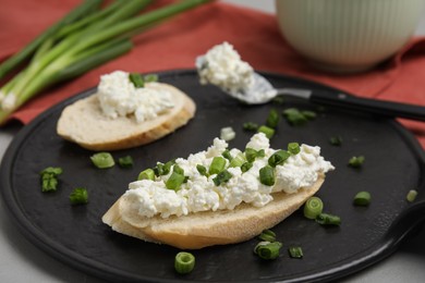 Photo of Bread with cottage cheese and green onion on grey table, closeup